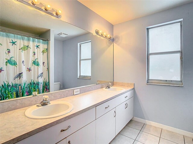 bathroom with tile flooring, double vanity, and toilet