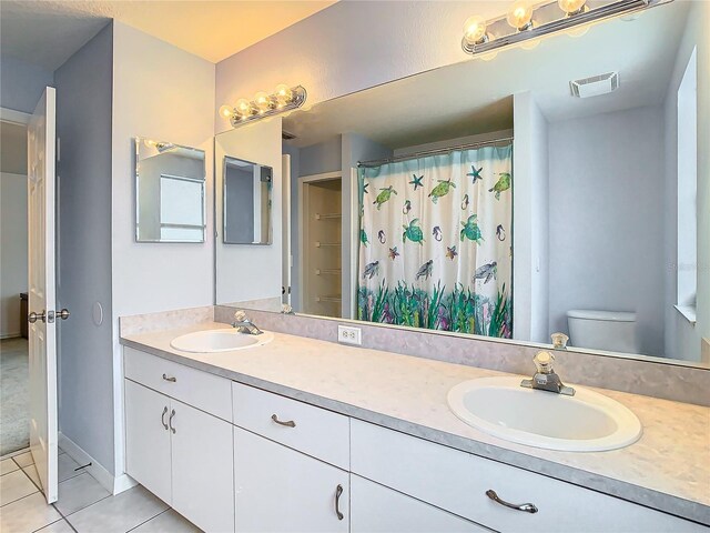 bathroom with tile flooring, toilet, and dual bowl vanity