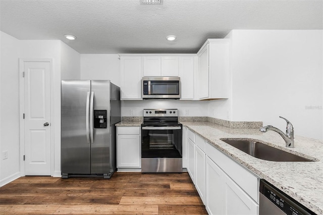 kitchen with dark hardwood / wood-style flooring, sink, stainless steel appliances, and light stone counters