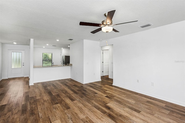 unfurnished living room with hardwood / wood-style floors, sink, ceiling fan, and a textured ceiling