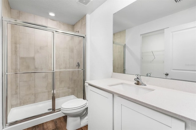 bathroom with toilet, a textured ceiling, an enclosed shower, vanity, and hardwood / wood-style flooring