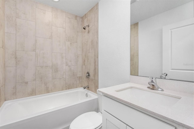 full bathroom featuring vanity, tiled shower / bath combo, toilet, and a textured ceiling