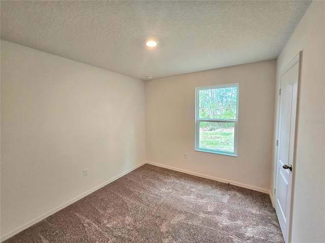 empty room with a textured ceiling and dark carpet