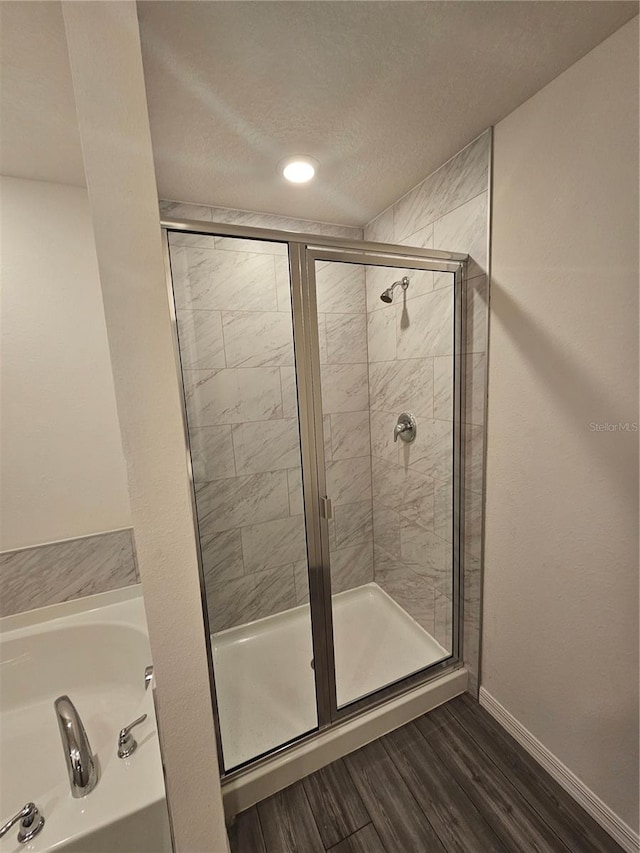 bathroom with wood-type flooring, shower with separate bathtub, and a textured ceiling