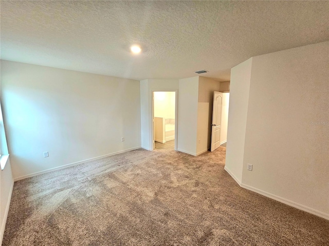 empty room with light colored carpet and a textured ceiling