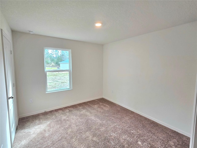 carpeted empty room featuring a textured ceiling