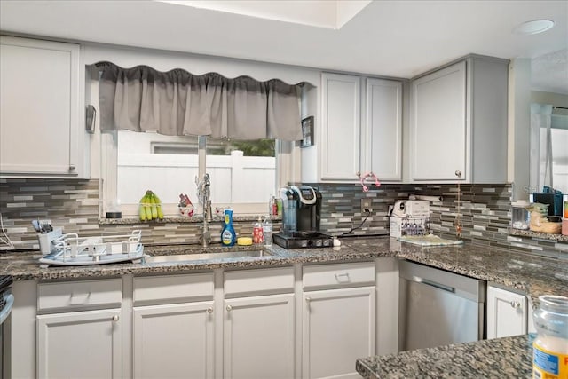 kitchen featuring dark stone countertops, backsplash, dishwasher, and white cabinetry