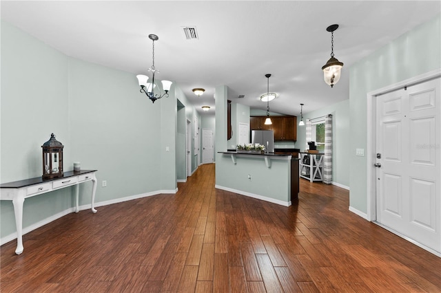 kitchen featuring dark hardwood / wood-style flooring, stainless steel refrigerator, kitchen peninsula, and a breakfast bar area