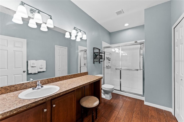 bathroom featuring wood-type flooring, toilet, vanity with extensive cabinet space, and walk in shower