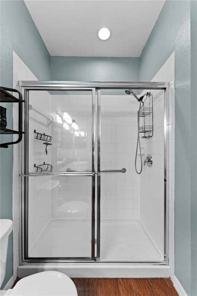 bathroom with a shower with shower door, toilet, and hardwood / wood-style flooring