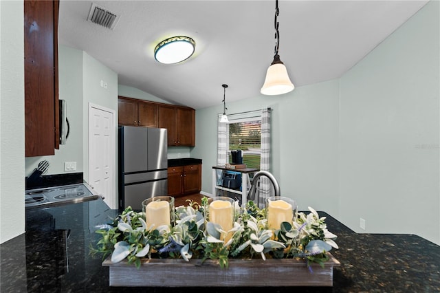 kitchen with appliances with stainless steel finishes, sink, dark stone counters, hanging light fixtures, and vaulted ceiling