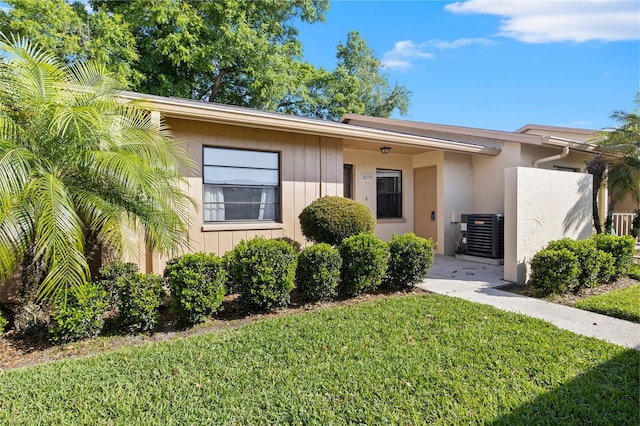 view of front of home with a front lawn and central AC