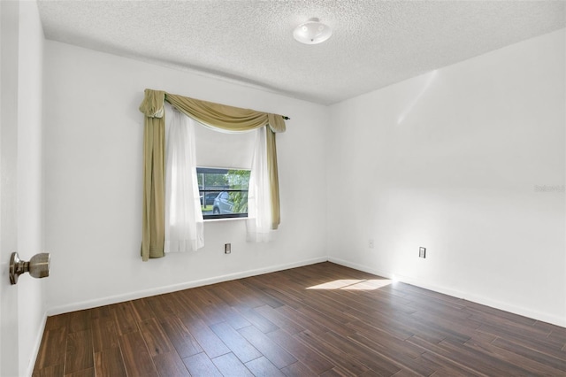 spare room featuring dark hardwood / wood-style floors and a textured ceiling