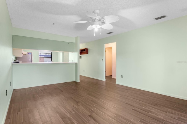 unfurnished living room featuring ceiling fan, dark hardwood / wood-style floors, and a textured ceiling