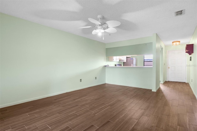 empty room featuring ceiling fan, a textured ceiling, and dark wood-type flooring