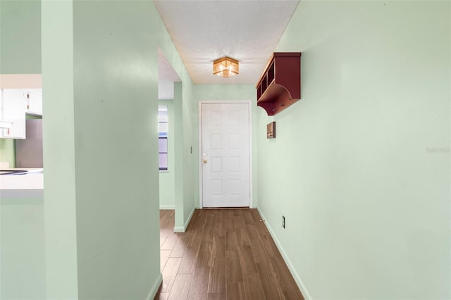 hallway with a textured ceiling and hardwood / wood-style floors