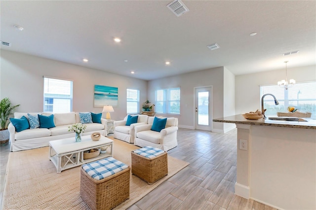 living room featuring an inviting chandelier, sink, and light wood-type flooring