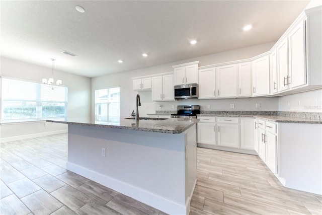 kitchen with a kitchen island with sink, sink, white cabinets, and appliances with stainless steel finishes