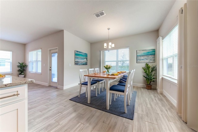 dining area featuring a notable chandelier, a wealth of natural light, and light wood-type flooring