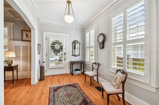 living area with ornamental molding and light wood-type flooring