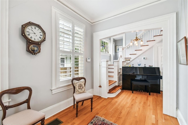 sitting room with ornamental molding and light hardwood / wood-style floors