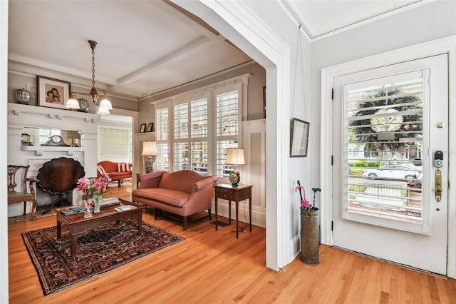 living area featuring ornamental molding, a healthy amount of sunlight, hardwood / wood-style floors, and a notable chandelier