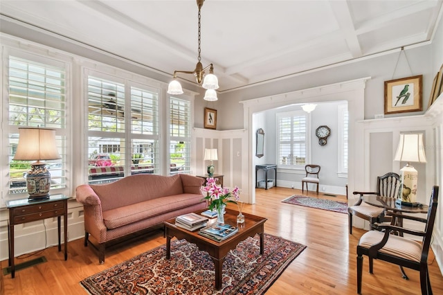 living room with hardwood / wood-style flooring, a notable chandelier, coffered ceiling, and beamed ceiling