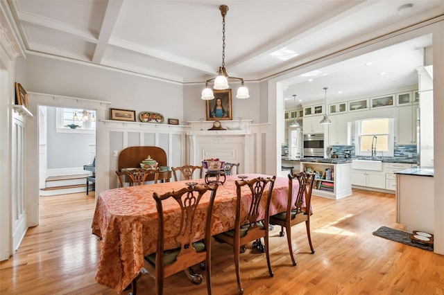 dining room featuring beamed ceiling, coffered ceiling, sink, and light wood-type flooring