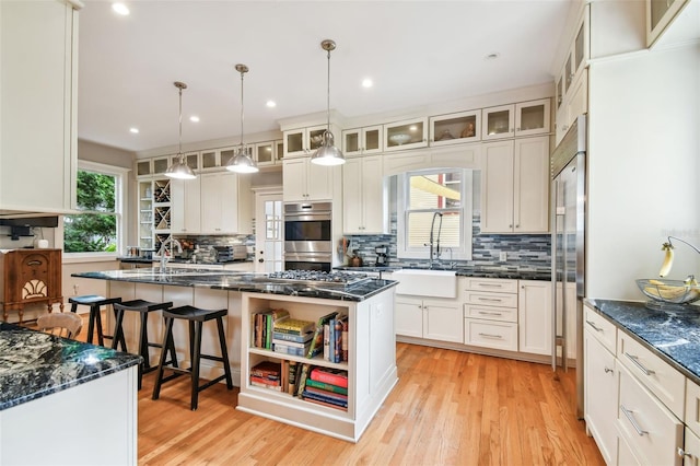 kitchen with sink, decorative light fixtures, a center island with sink, appliances with stainless steel finishes, and white cabinets