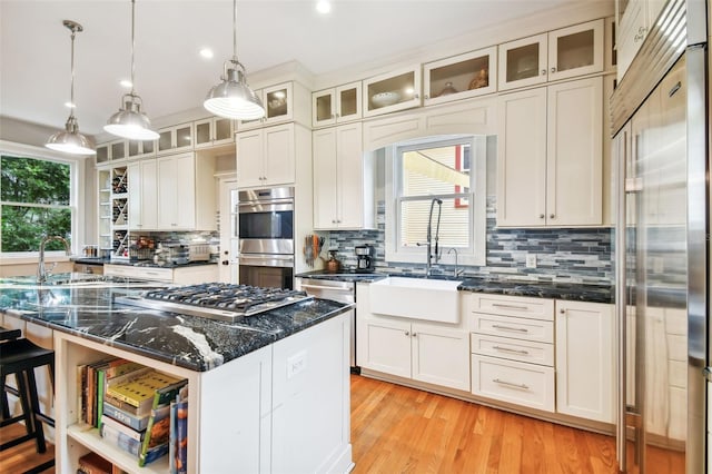 kitchen with pendant lighting, sink, appliances with stainless steel finishes, a center island, and dark stone counters