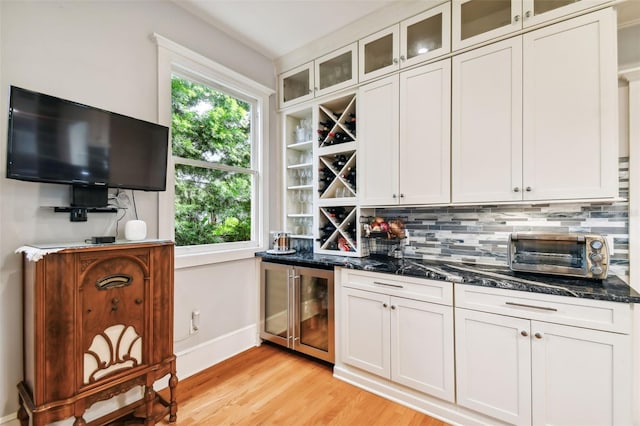 kitchen with white cabinetry, tasteful backsplash, a healthy amount of sunlight, beverage cooler, and dark stone counters