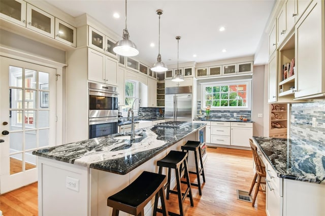 kitchen with a breakfast bar, dark stone countertops, hanging light fixtures, stainless steel appliances, and a spacious island