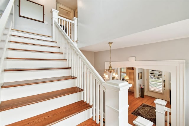 stairs featuring hardwood / wood-style flooring and a notable chandelier