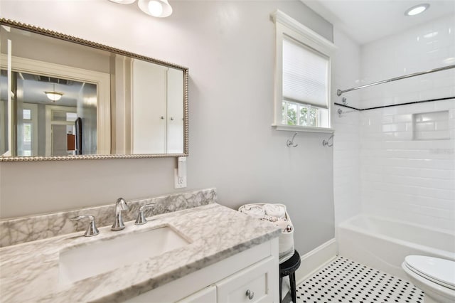 full bathroom featuring tile patterned flooring, vanity, tiled shower / bath, and toilet