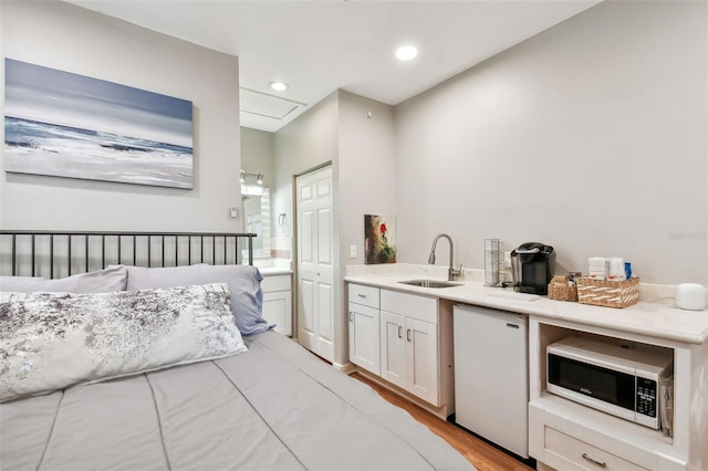 bedroom featuring sink, fridge, and light hardwood / wood-style floors