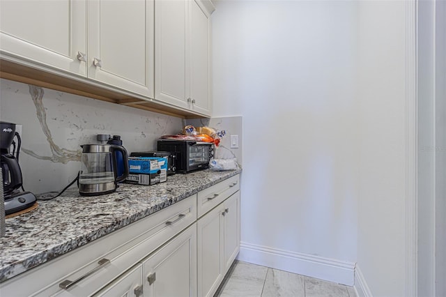 bar with white cabinets, decorative backsplash, light tile patterned flooring, and light stone countertops