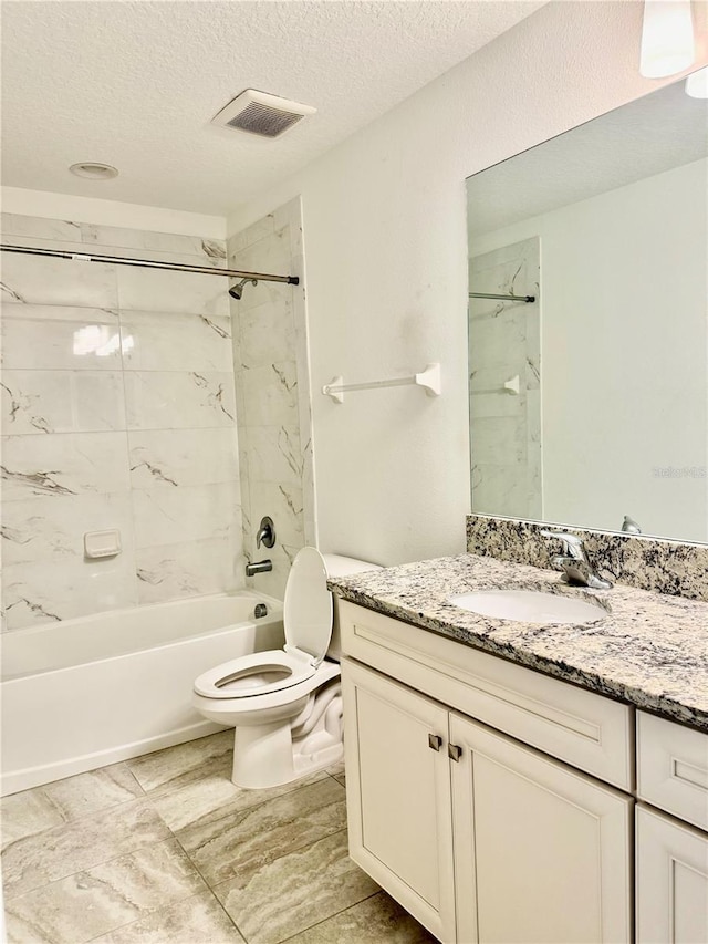 full bathroom with vanity, a textured ceiling, toilet, and tiled shower / bath