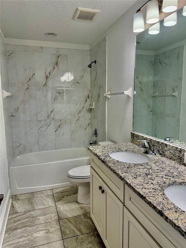 full bathroom with a textured ceiling, vanity, tiled shower / bath combo, and toilet