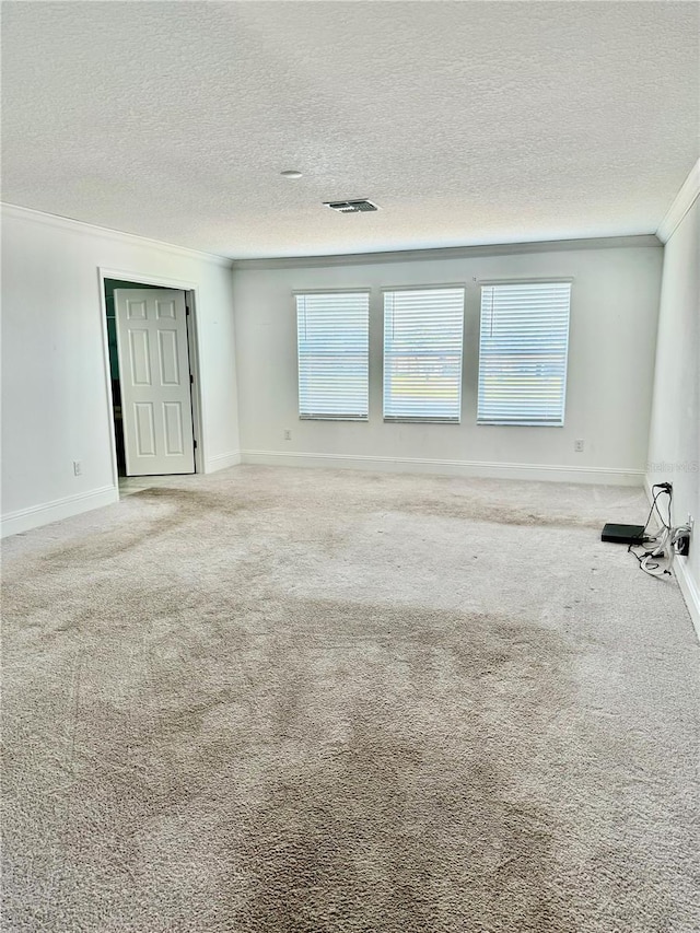 carpeted empty room with ornamental molding and a textured ceiling