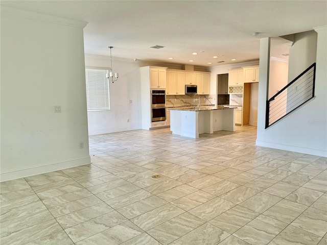 kitchen featuring white cabinetry, hanging light fixtures, a notable chandelier, an island with sink, and appliances with stainless steel finishes