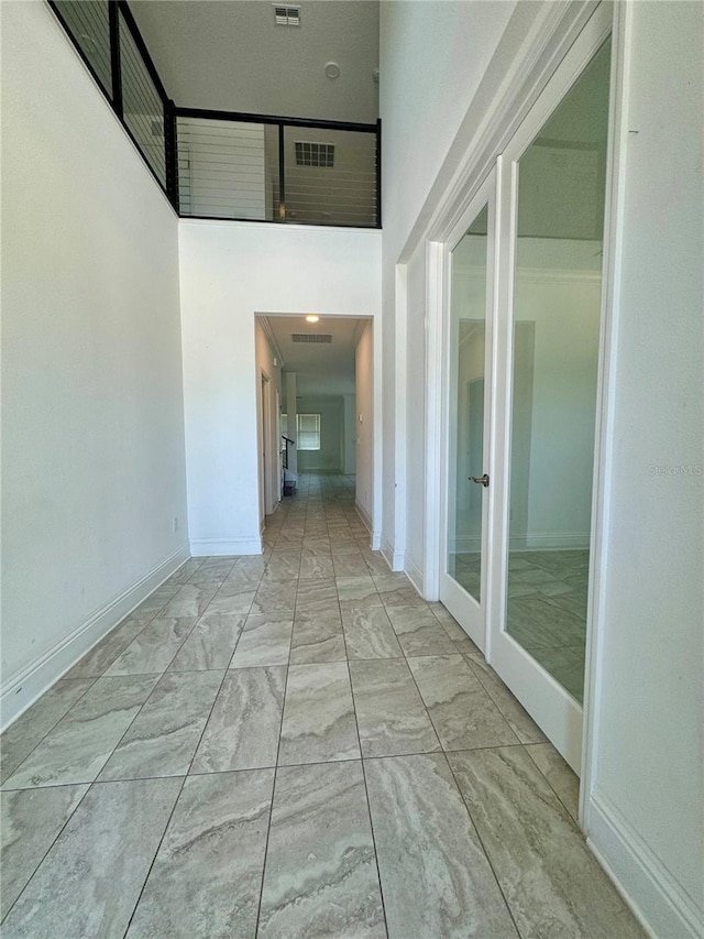 hall featuring a towering ceiling and french doors