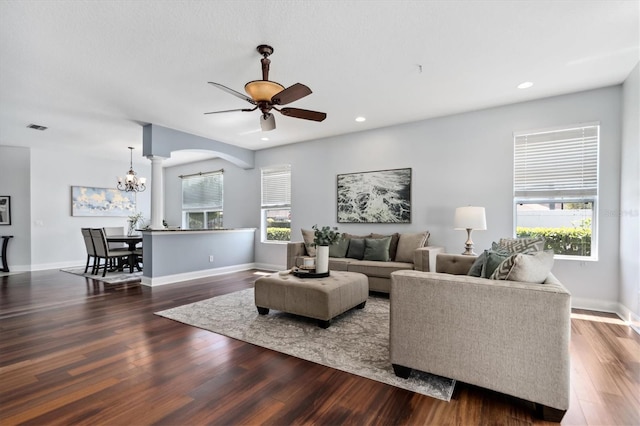 living room with dark hardwood / wood-style flooring, ceiling fan with notable chandelier, and a wealth of natural light