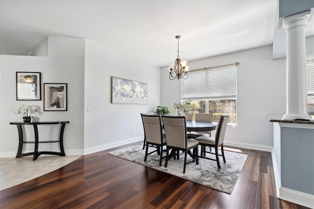 tiled dining area featuring decorative columns and a chandelier