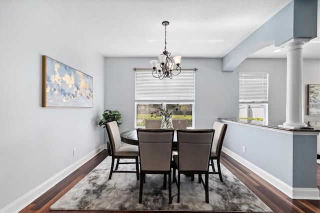 dining room with dark hardwood / wood-style flooring, ornate columns, and a notable chandelier