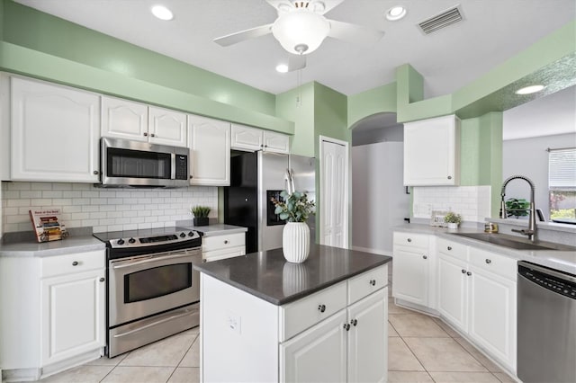 kitchen featuring ceiling fan, stainless steel appliances, tasteful backsplash, white cabinets, and sink