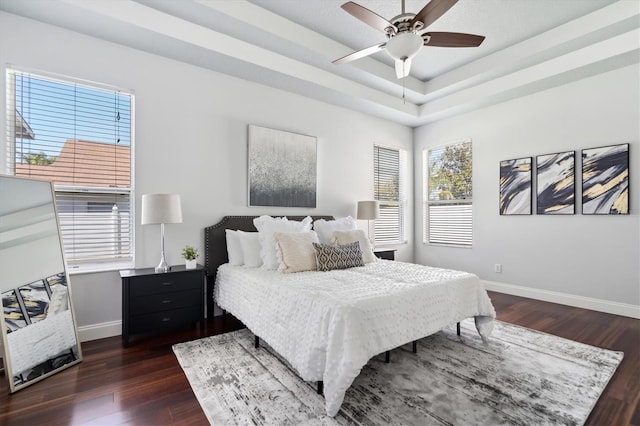 bedroom featuring ceiling fan, a raised ceiling, and dark hardwood / wood-style floors