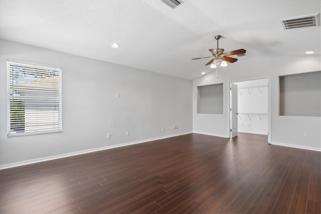 empty room with a textured ceiling, dark hardwood / wood-style flooring, ceiling fan, and vaulted ceiling