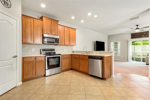 kitchen with kitchen peninsula, ceiling fan, stainless steel appliances, tasteful backsplash, and light tile floors