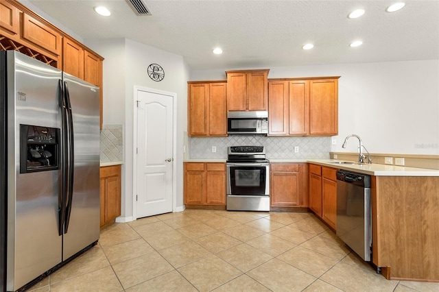 kitchen with kitchen peninsula, stainless steel appliances, tasteful backsplash, sink, and light tile floors