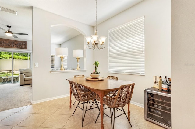 tiled dining area with beverage cooler and ceiling fan with notable chandelier